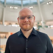 Jon Brown, CTO at Groom AI, in a black shirt and glasses in a bright atrium.