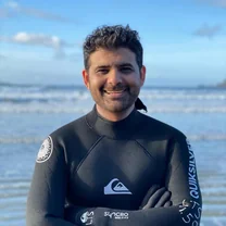 Rafique Awan, Product Owner at Mastercard Canada, in a wetsuit on a beach.